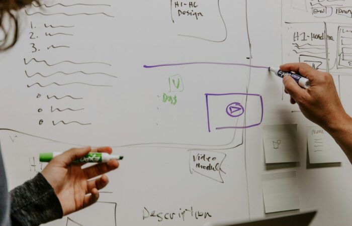 two people drawing on whiteboard